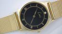 Close-up, angled view of the gold Limit dial with black face, Roman numerals, and diamond marker.