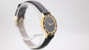Angled view of the Amara watch on a stand, showing the crown and the curve of the black leather strap.