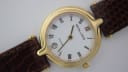 Close-up front view of Solvil et Titus Sonville gold-tone watch with white dial and roman numerals, showing date window.