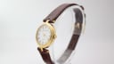 Side view of the Solvil et Titus Sonville gold-tone watch on a display stand, highlighting the crown and curved case profile.
