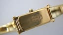 Close-up of the gold tone case back showing '1500' engraving and the stylised Gucci crest.