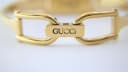 Close-up of the gold tone bracelet's deployment clasp with 'GUCCI' engraved.