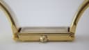 Close-up side view of the watch case and crown, revealing the texture of the gold tone finish.