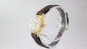 Angled side view of the Slava watch, showing the gold-tone case and fluted crown.