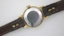 View of the brushed stainless steel case back of the Slava watch and the brown leather strap.