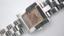Close-up top-down view of the Tissot L730K brown dial with applied baton markers and silver hands.