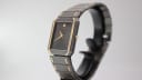 Angled side view of the Seiko watch showing the case profile and integrated bracelet, on a stand.