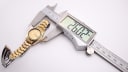 The Seiko watch being measured by a digital caliper, displaying a case diameter of 26.02mm.