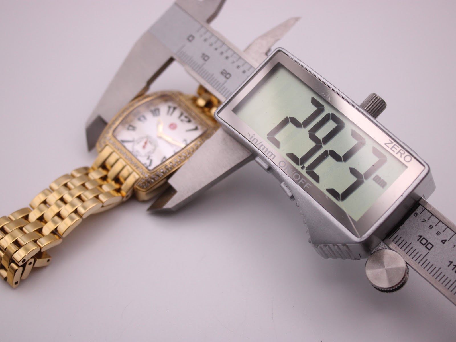 Angled view of the gold-tone Michele watch, showcasing the curved case and bracelet design from the right side.