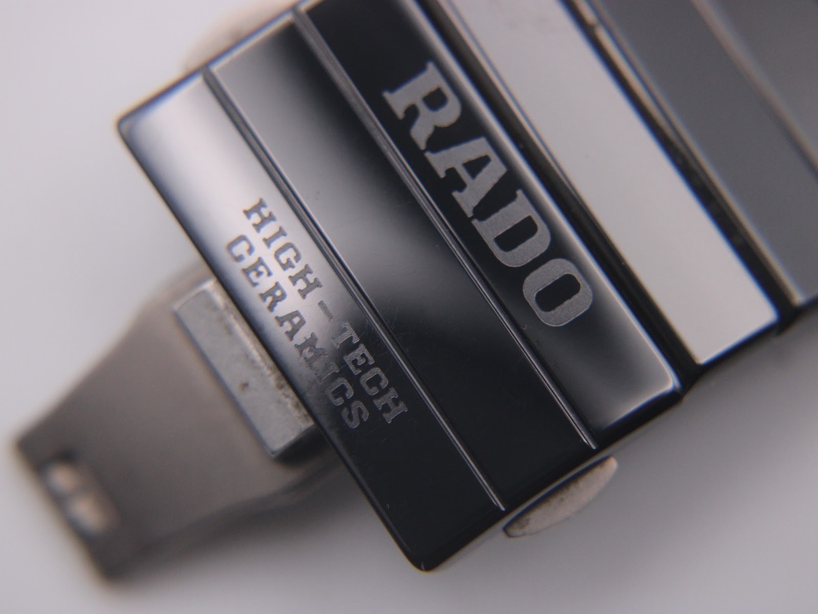 Close-up of the Rado Diastar bracelet clasp, with "RADO" and "HIGH-TECH CERAMICS" embossed on the black ceramic links.