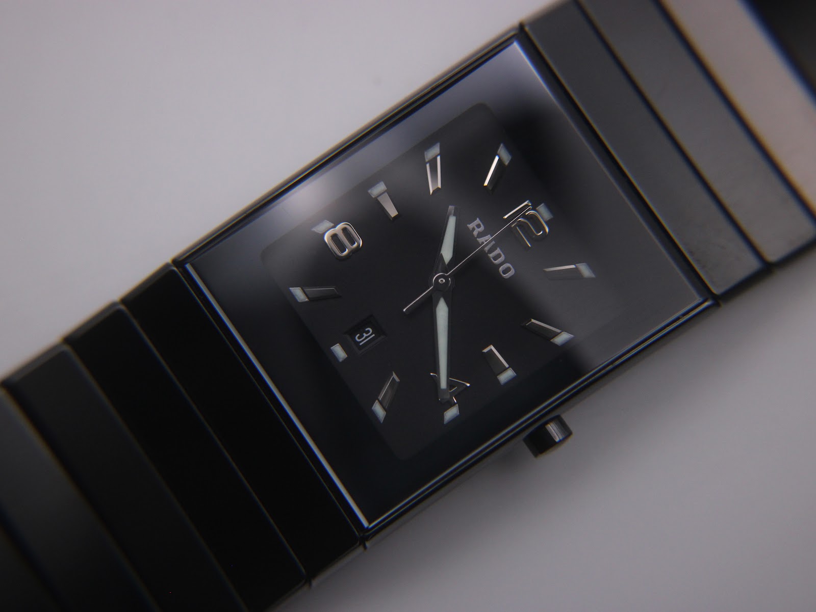 Close-up of the black dial of the Rado Diastar, displaying applied baton indices and Arabic numerals, luminous hands, and the date window at 6 o'clock.