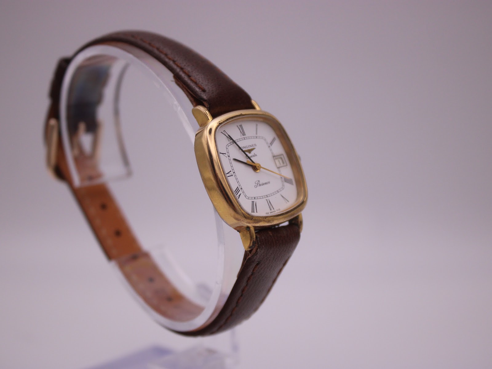 Side view of Longines Presence watch highlighting the watch profile and crown, brown strap on clear stand.