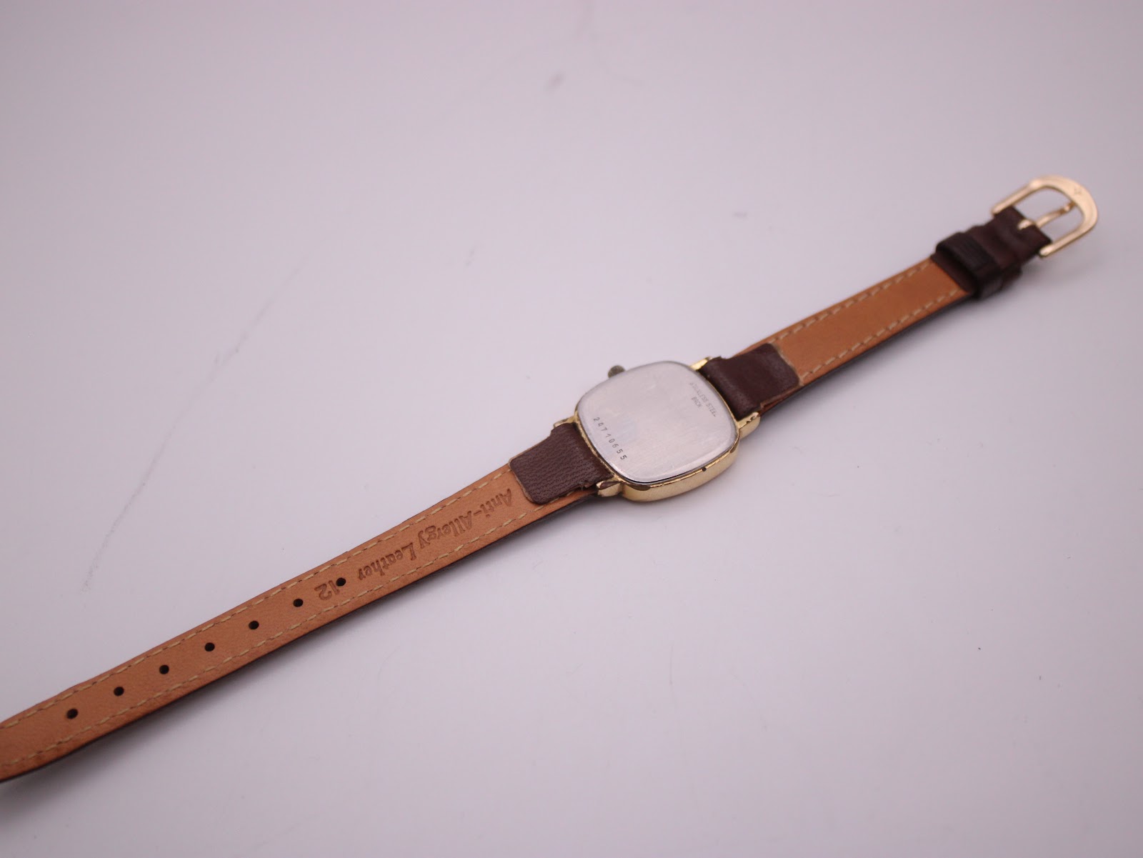 Back view of the Longines Presence watch laid flat, showing the case back and the underside of the brown leather strap with 'Anti-Allergy Leather' text.