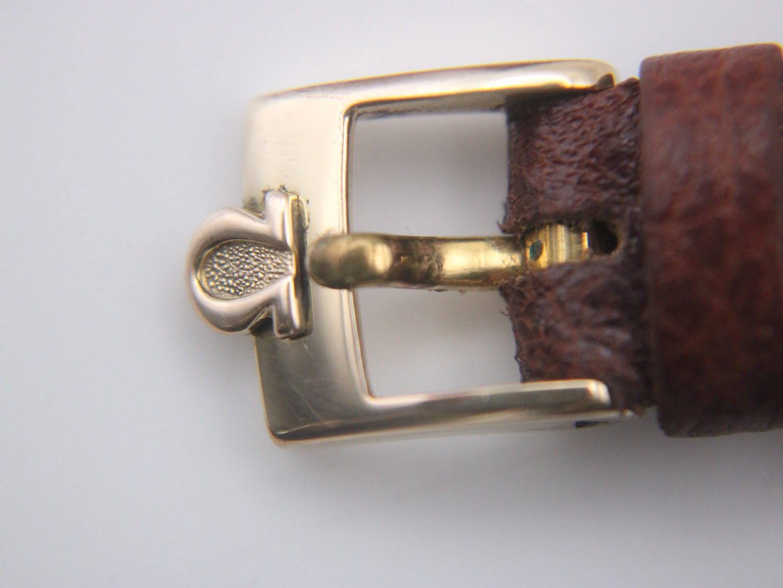 Close-up of the original gold-coloured buckle with the Omega logo.