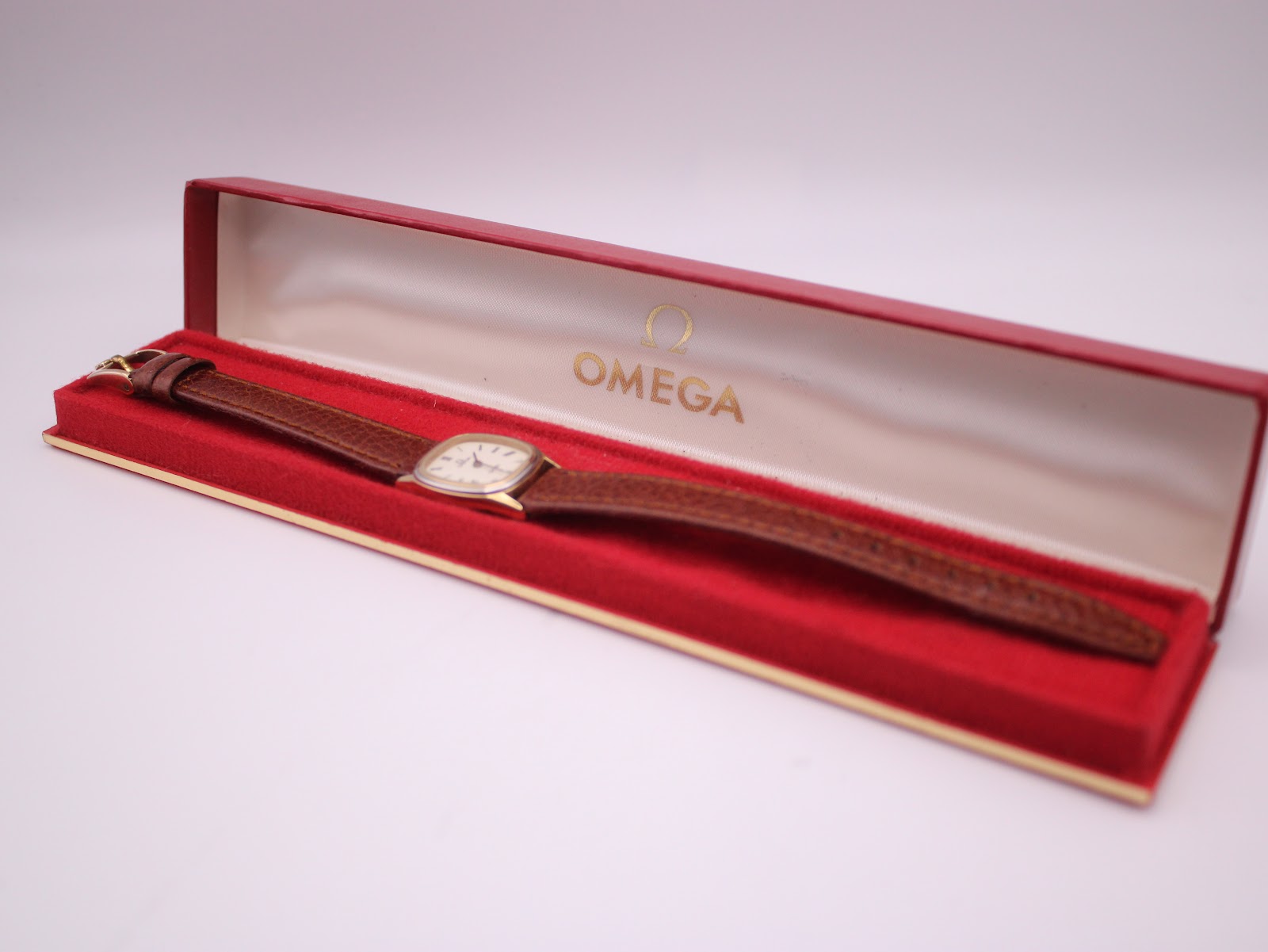 The Omega De Ville watch presented inside its red original Omega box with gold interior.