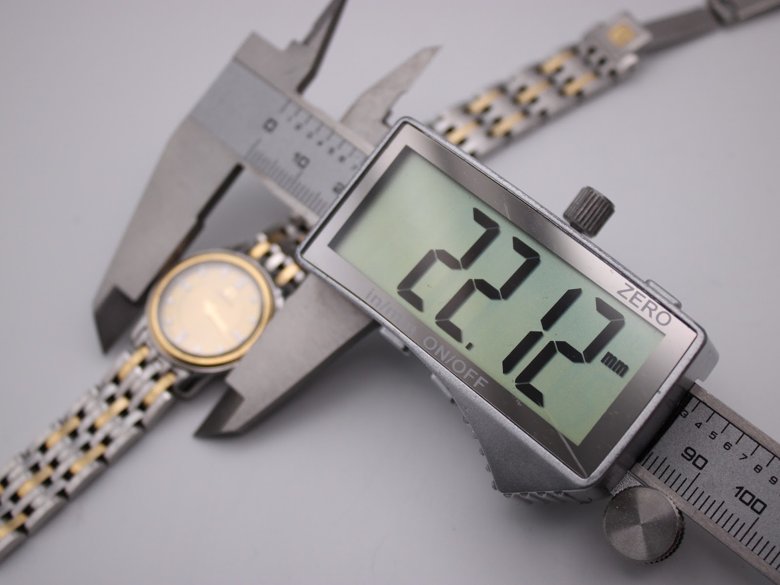 Digital caliper measuring the Omega watch case diameter at 22.12mm.