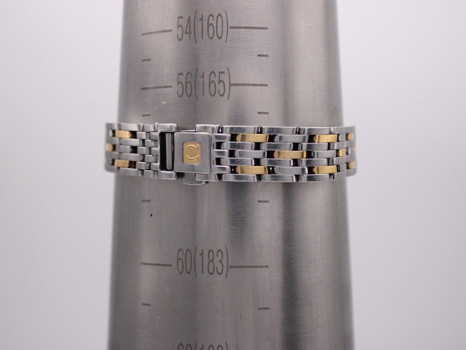 Omega two-tone bracelet on a wrist sizing gauge, indicating a wrist circumference of 16.5cm.