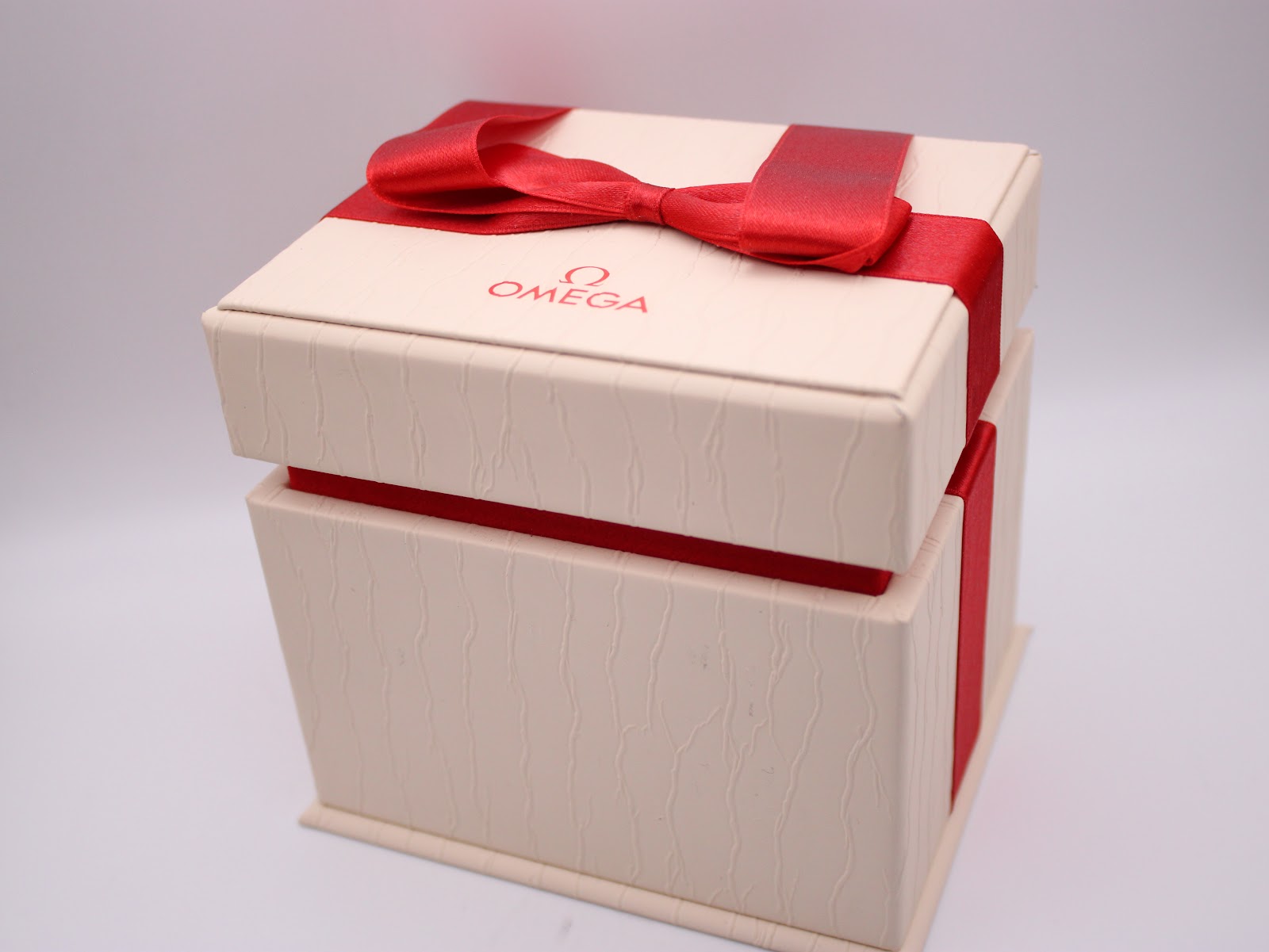 Exterior view of the original Omega watch box, tied with a red ribbon.