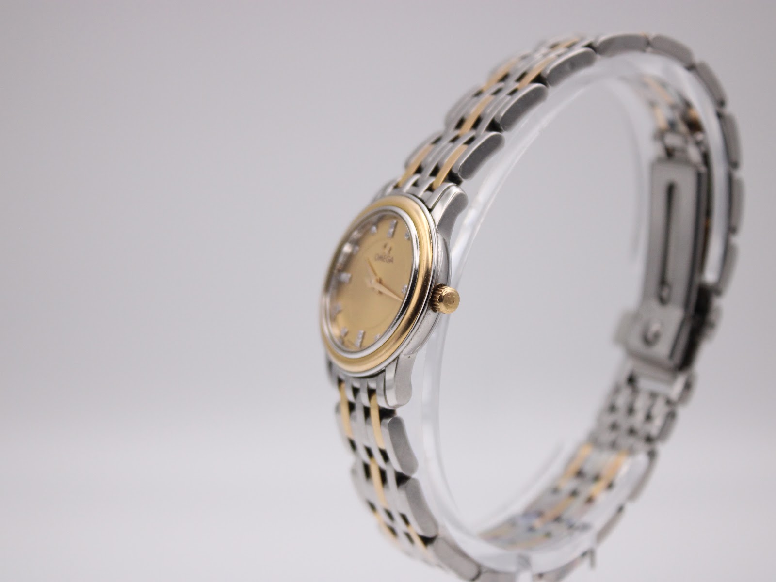 Angled side view of the Omega watch on a display stand, highlighting the two-tone case and bracelet.