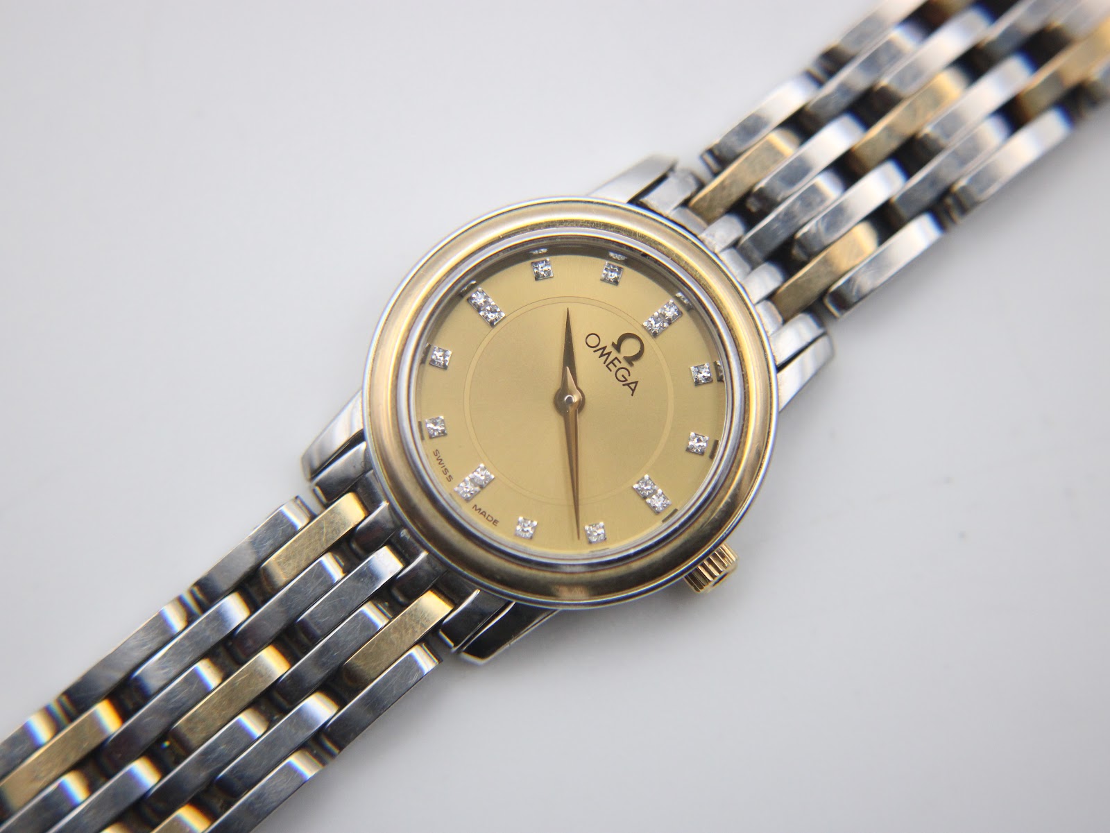 Close-up, face-on view of the Omega gold dial with diamond hour markers and gold hands.