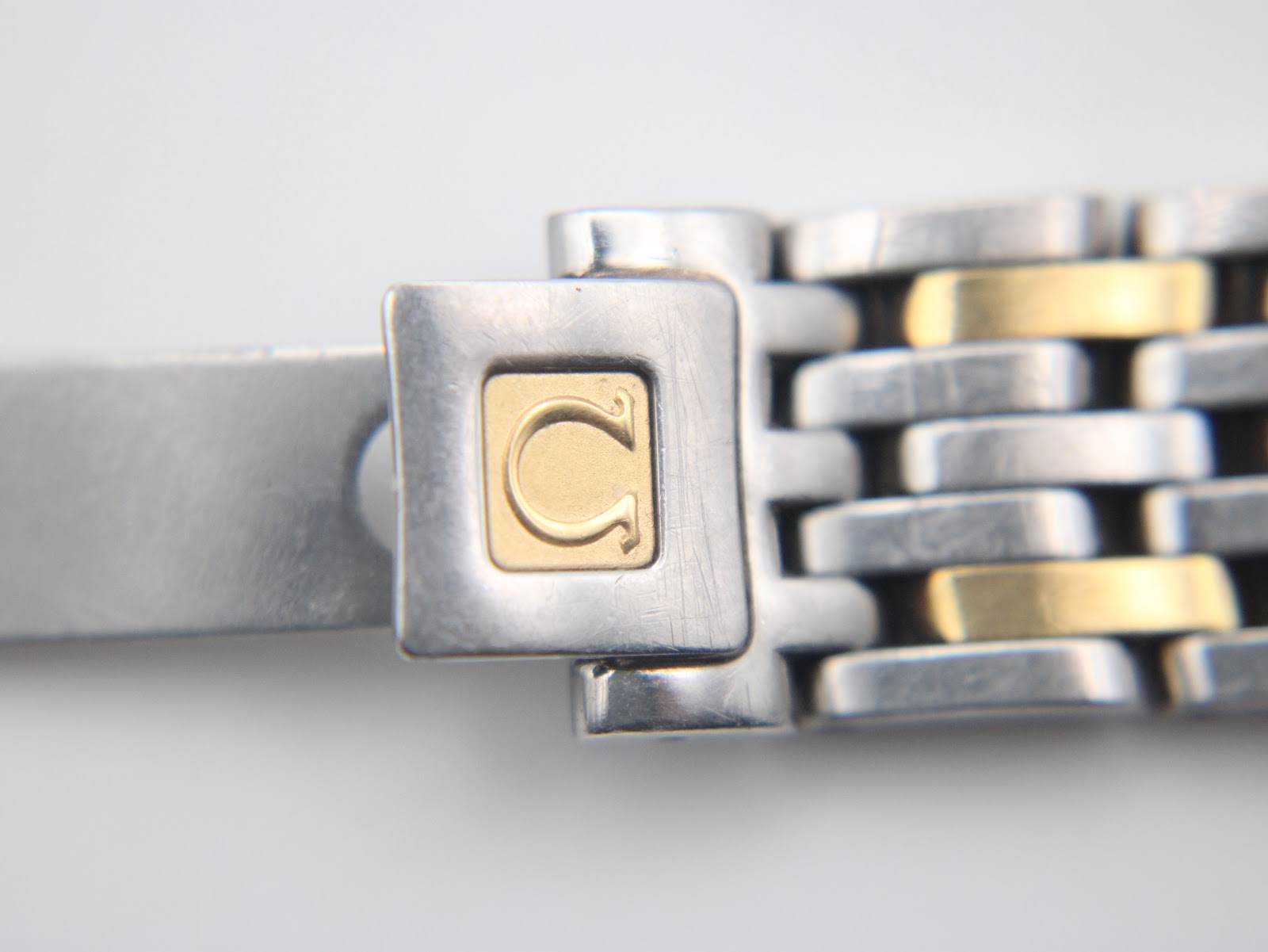 Close-up of the two-tone bracelet's signed folding clasp, featuring the Omega logo in gold.