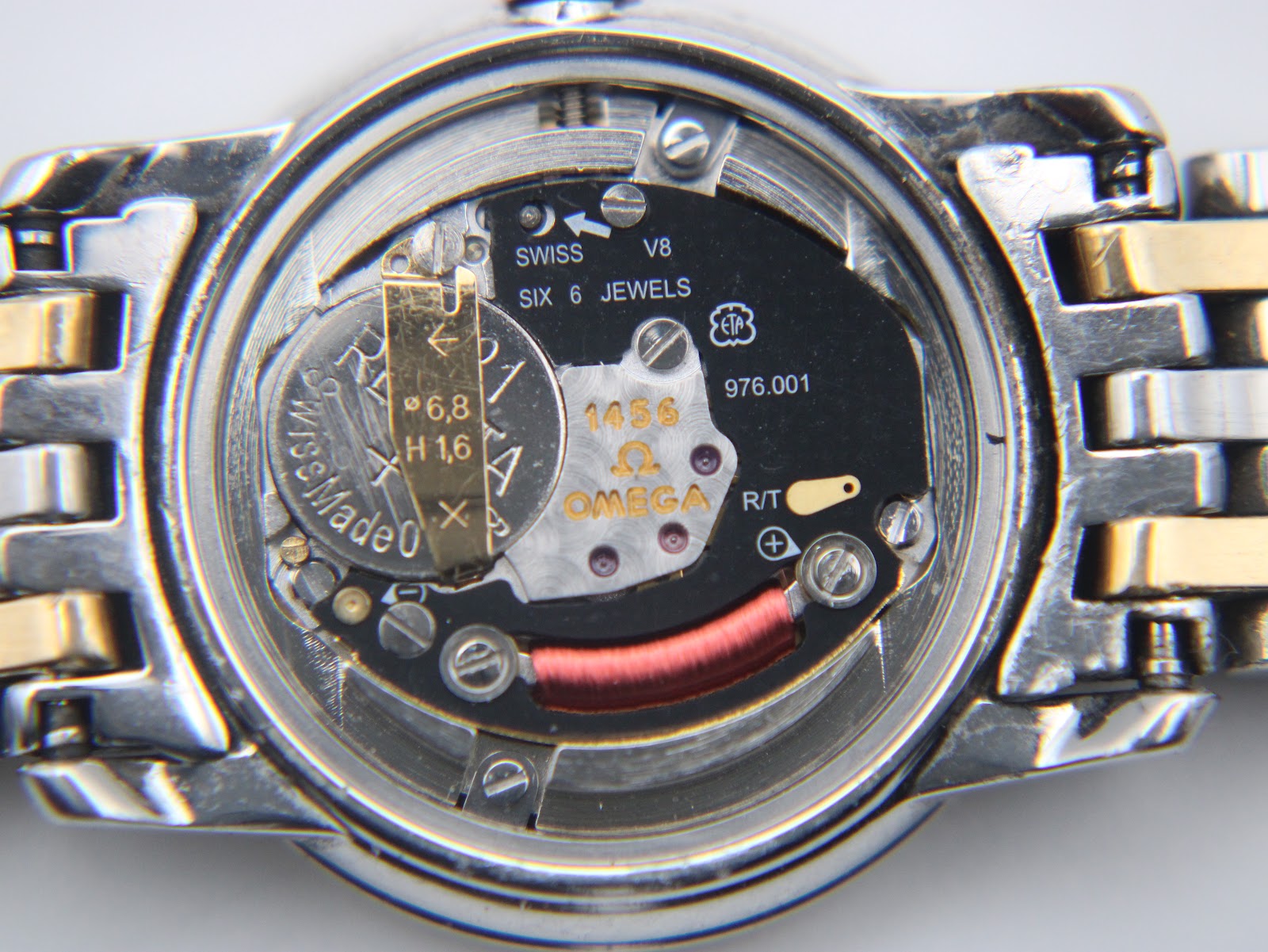 Open case back showing the Swiss ETA 976.001 quartz movement with six jewels and Omega branding.