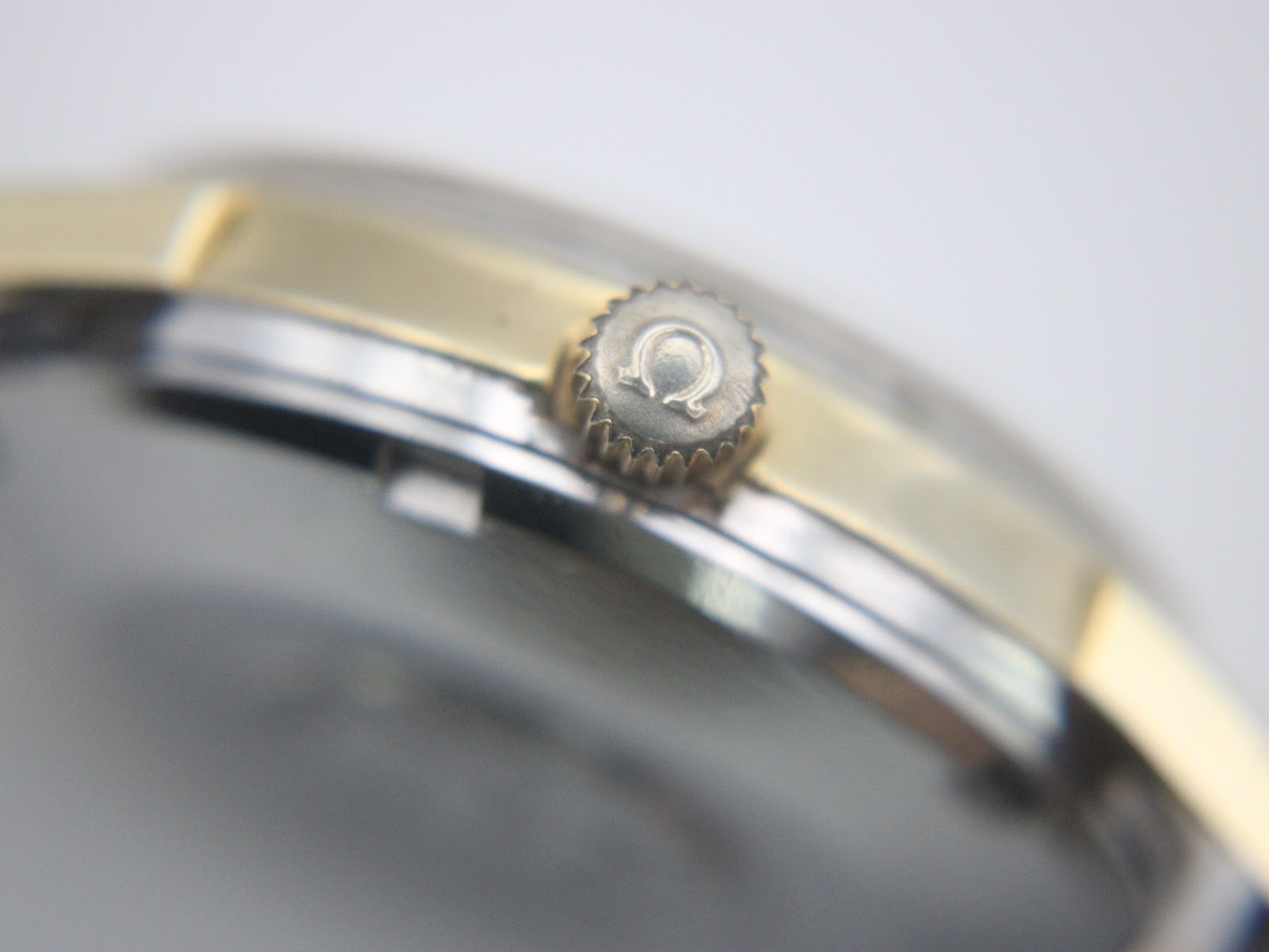 Close-up of the omega-signed crown on the gold-toned case.