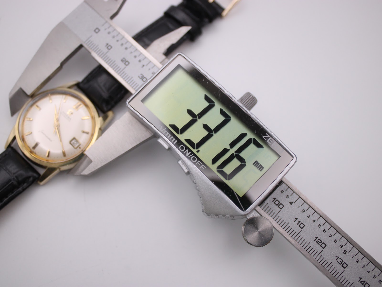 Digital caliper measuring the case diameter of the omega seamaster watch at 33.16mm.
