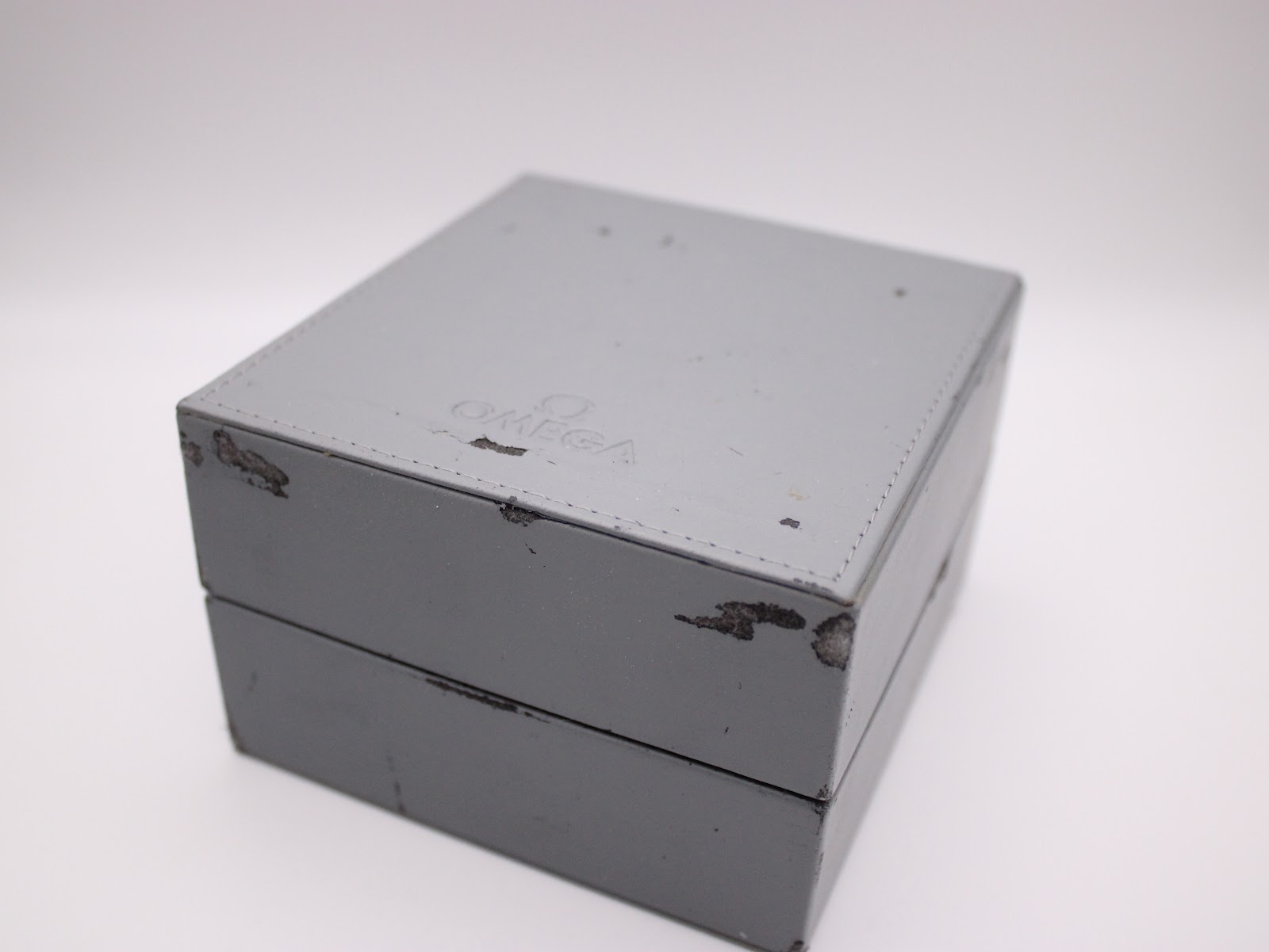 Top view of the closed original grey omega watch box, showing wear on edges.