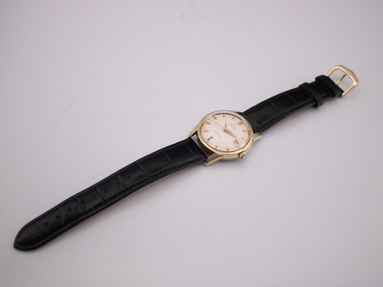 Overhead view of the omega seamaster watch with its black leather strap laid flat.