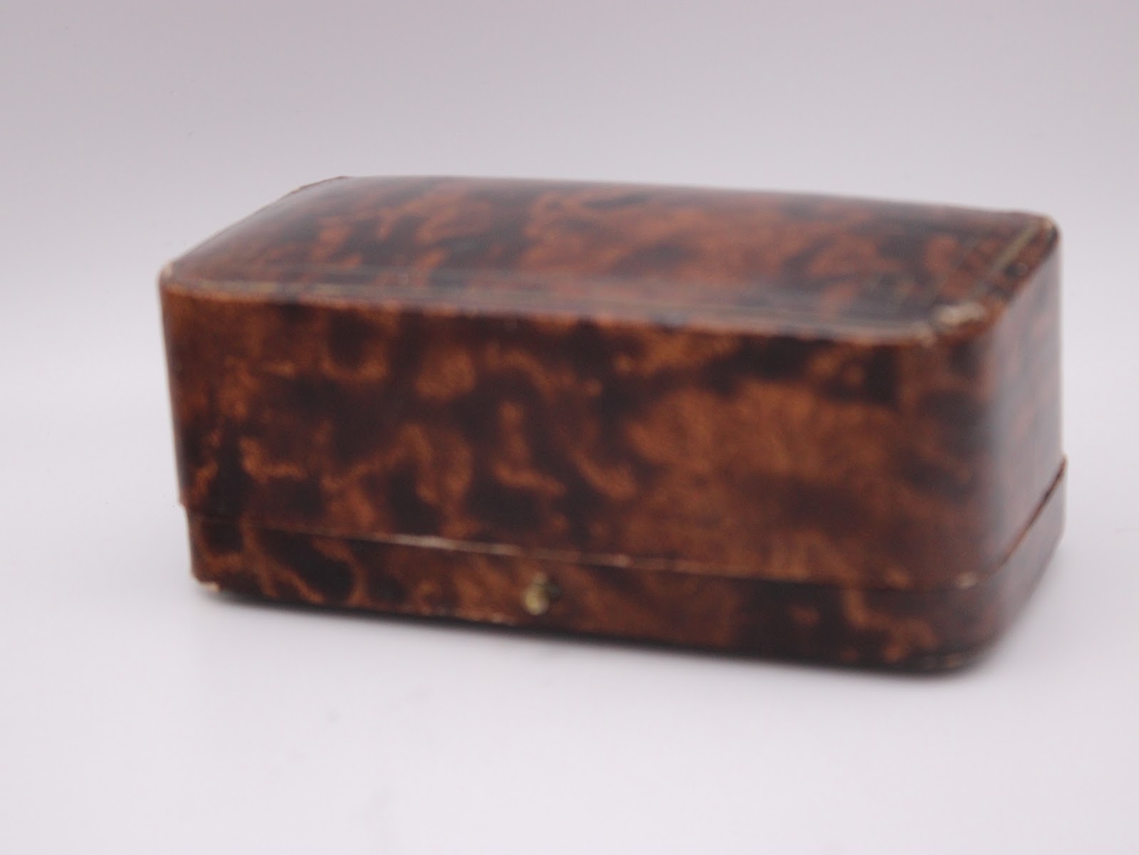 Closed view of the original brown faux tortoise shell presentation box for the Omega watch.