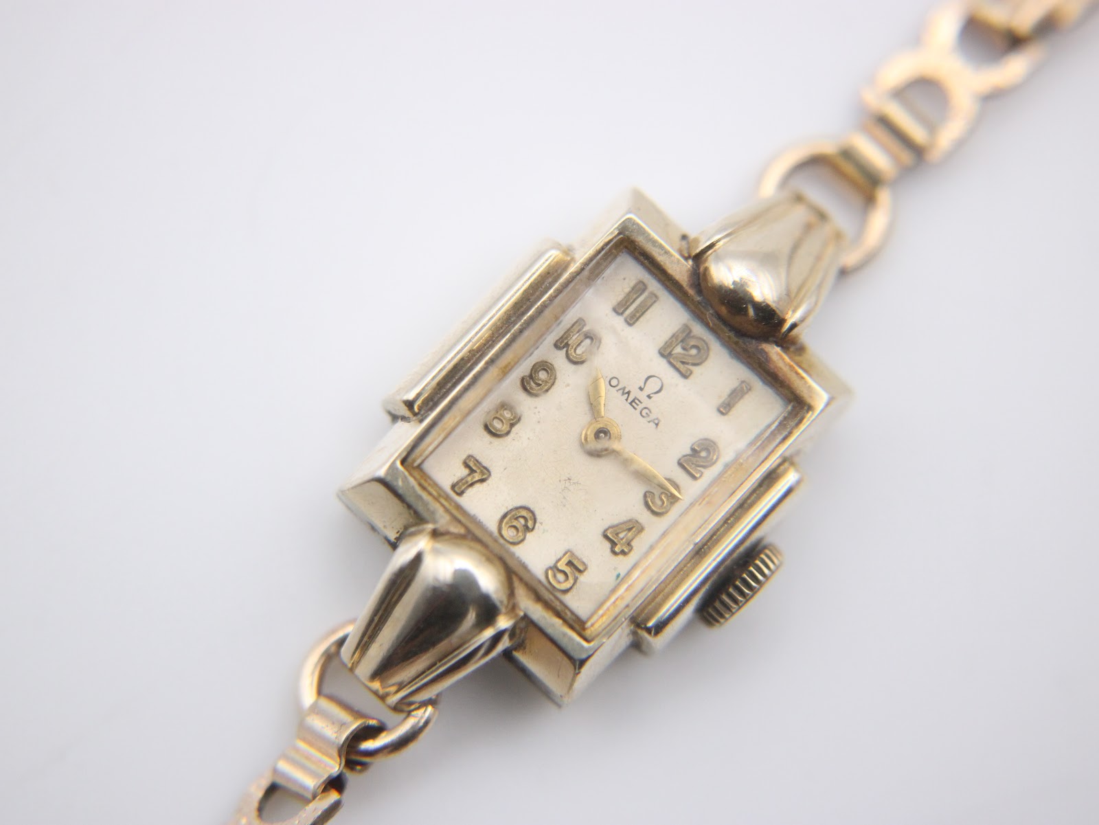 Close-up, slightly angled view of the Omega watch dial, showing applied Arabic numerals and Omega logo.