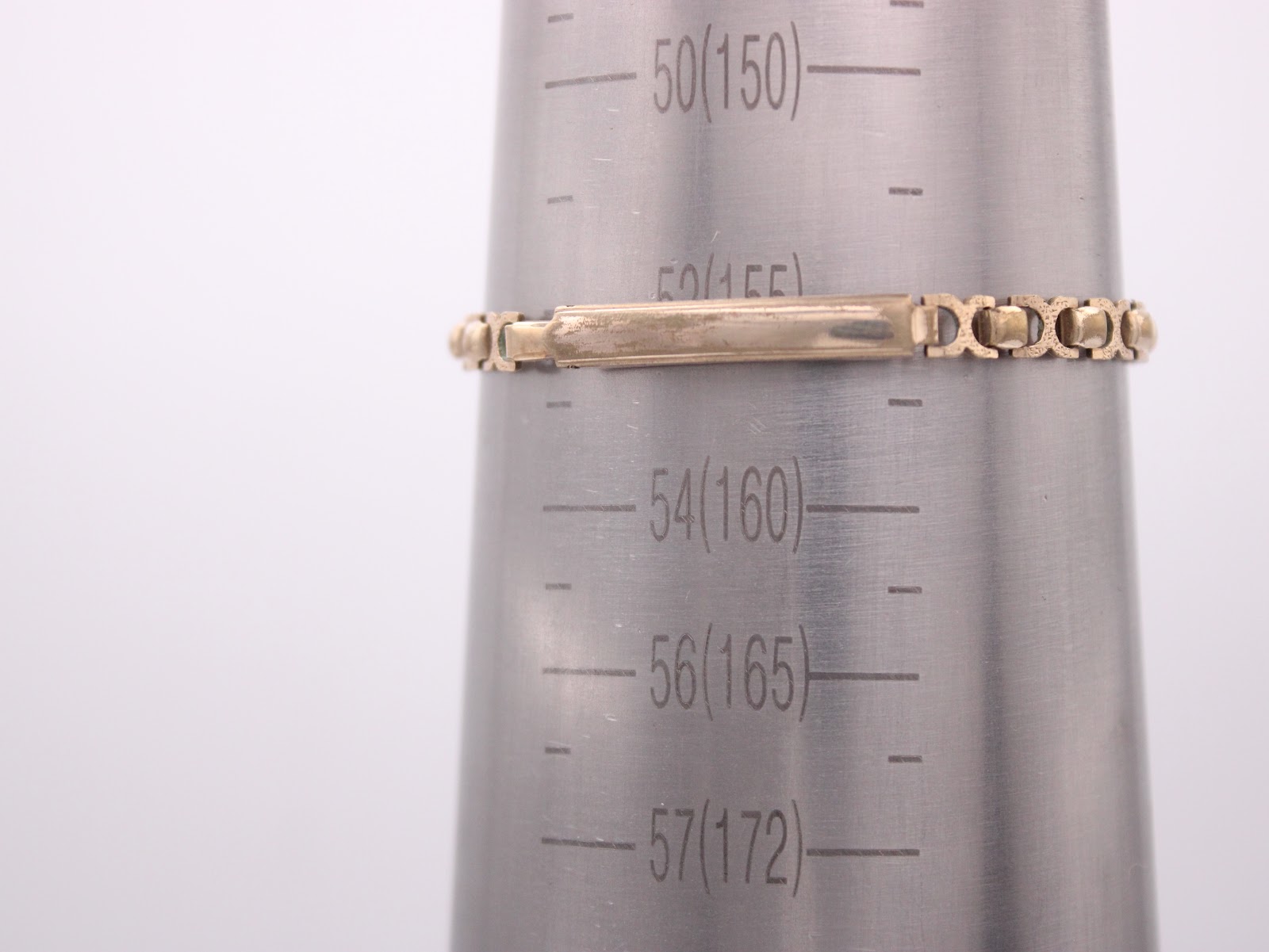 The gold-tone bracelet of the Omega watch measured on a wrist sizing gauge, showing a circumference of approximately 15.3cm.