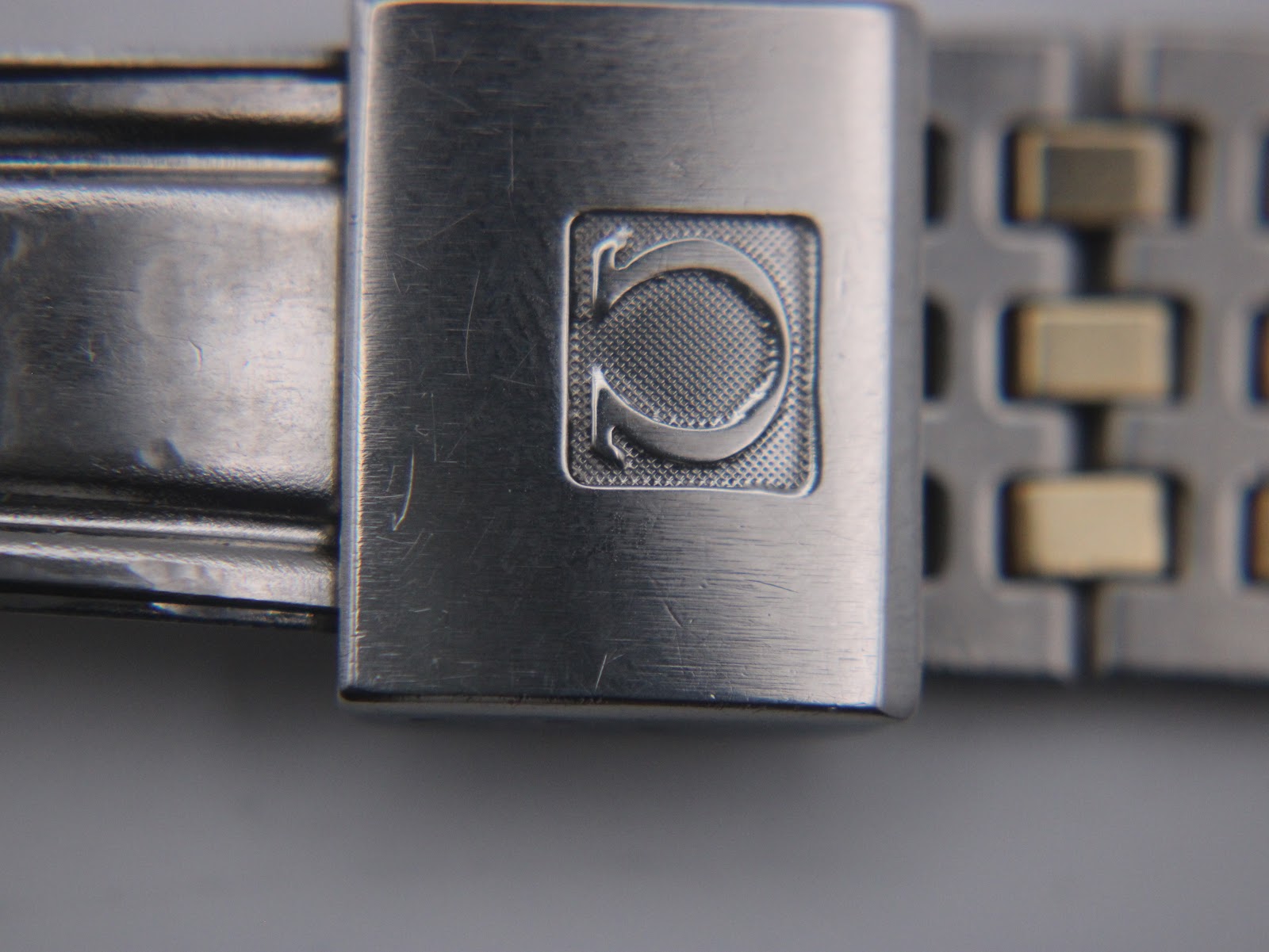 Close-up of the Omega-signed fold-over clasp on the bracelet.