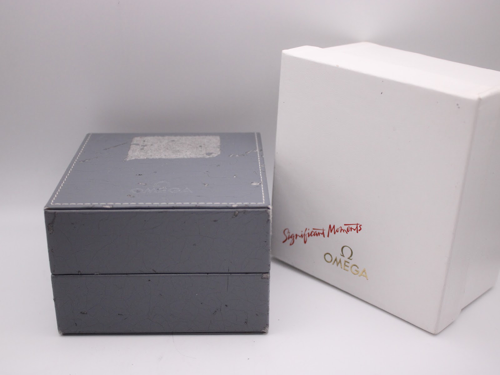The exterior of the original grey Omega watch box alongside its white outer sleeve, with 'Significant Moments' text.