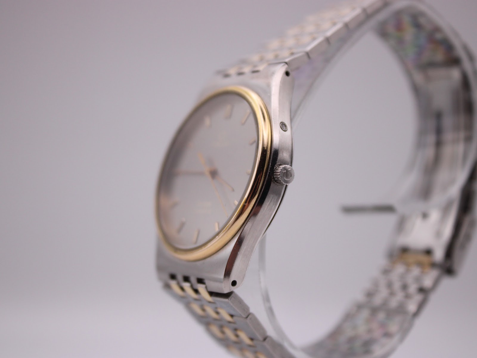 Side view of the Omega De Ville showing the slim case profile, crown, and two-tone bracelet.
