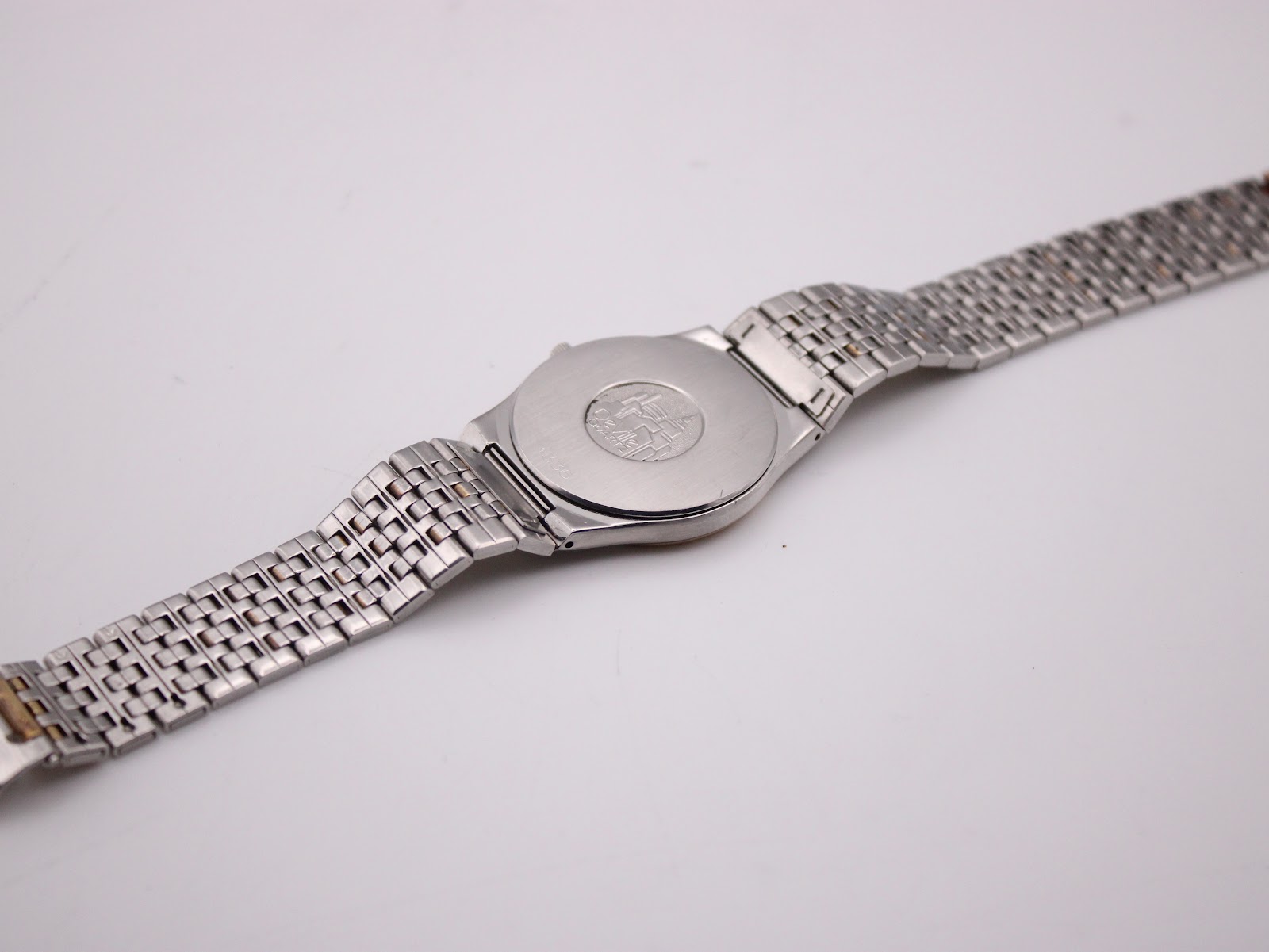 View of the watch back and the full two-tone bracelet laid flat, showing the case back emblem.