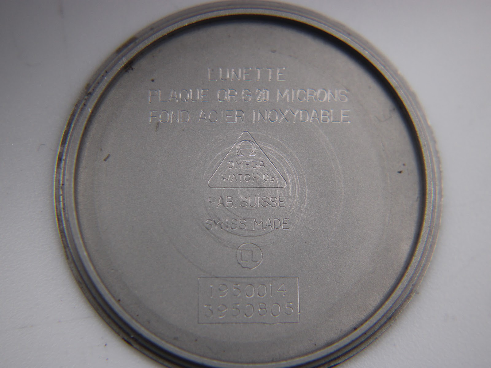 Inside case back engraving, revealing 'LUNETTE PLAQUE OR G 20 MICRONS' and 'FOND ACIER INOXYDABLE'.