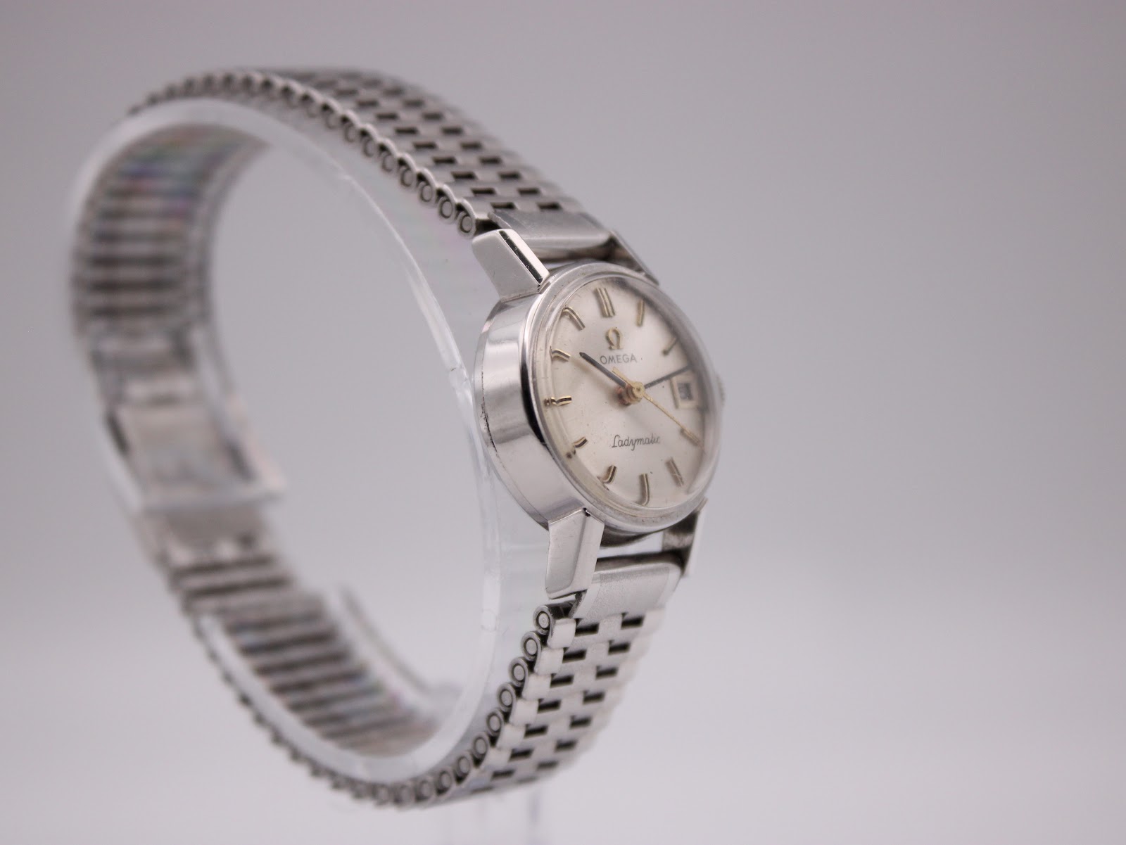 Angled view of the Omega Ladymatic on a stand, highlighting the bracelet's intricate ladder link design.