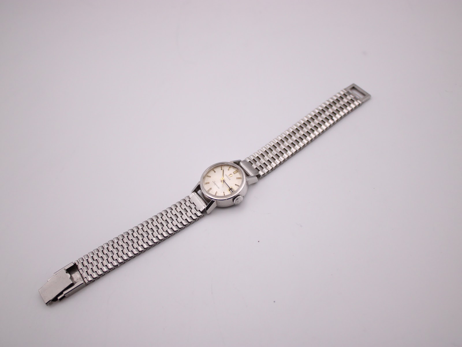 Top-down view of the Omega Ladymatic watch with its stainless steel bracelet extended, against a white background.