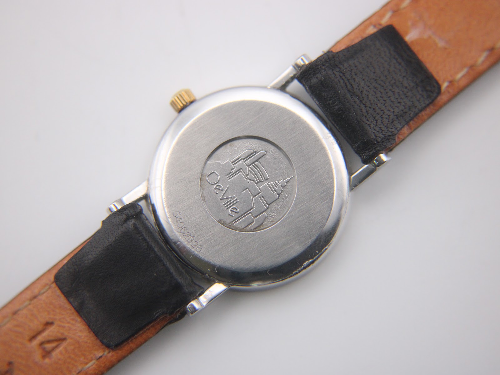 Close-up, top-down view of the Omega De Ville's white dial with black Roman numerals and date window at 3 o'clock.