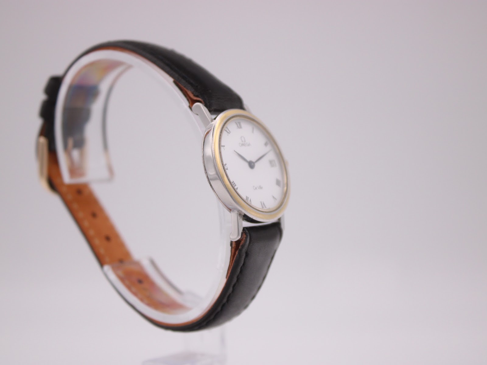 Close-up of the brushed stainless steel case back of the Omega De Ville, showing the embossed logo and serial number.