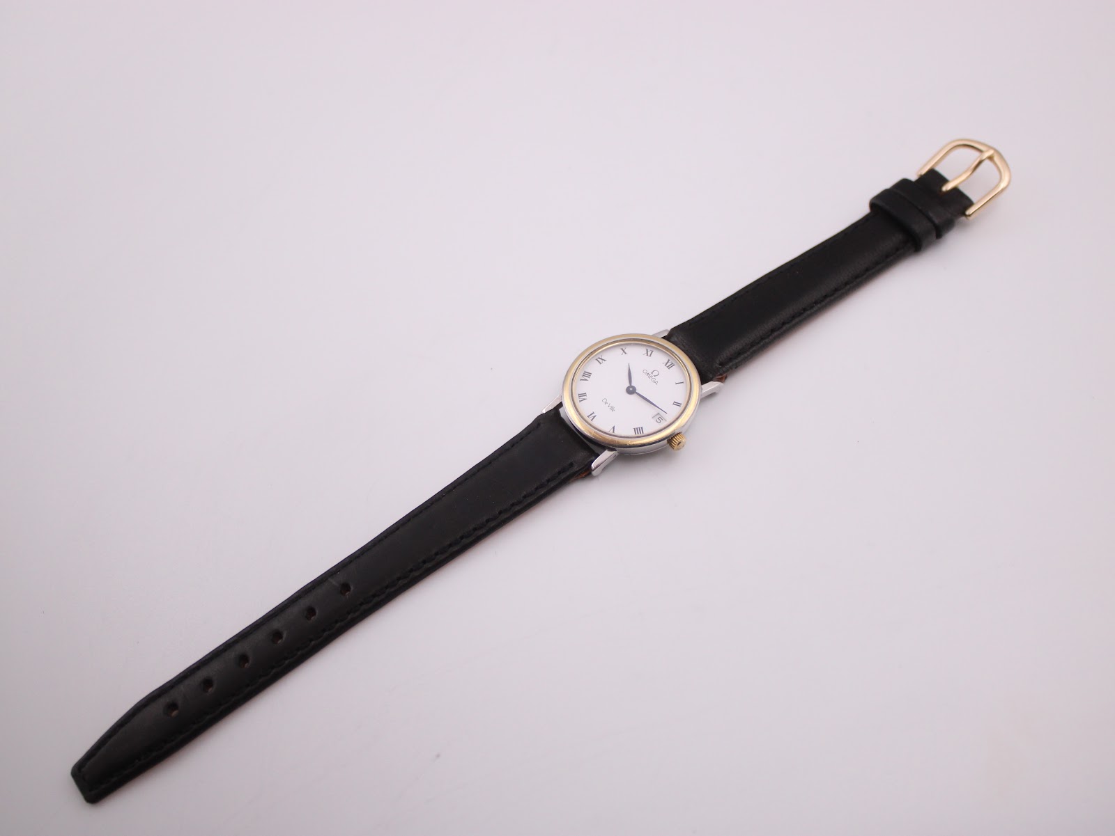 Full overhead view of the Omega De Ville watch with its black leather strap fully extended on a white background.