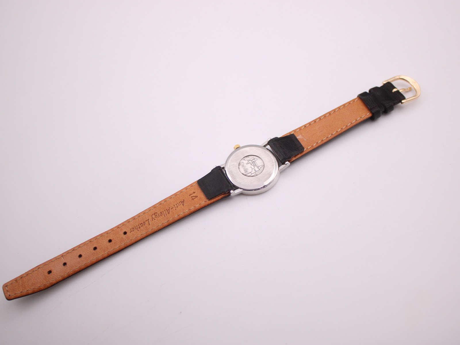 Full rear view of the Omega De Ville watch, showing the light brown underside of the leather strap and gold-toned buckle.