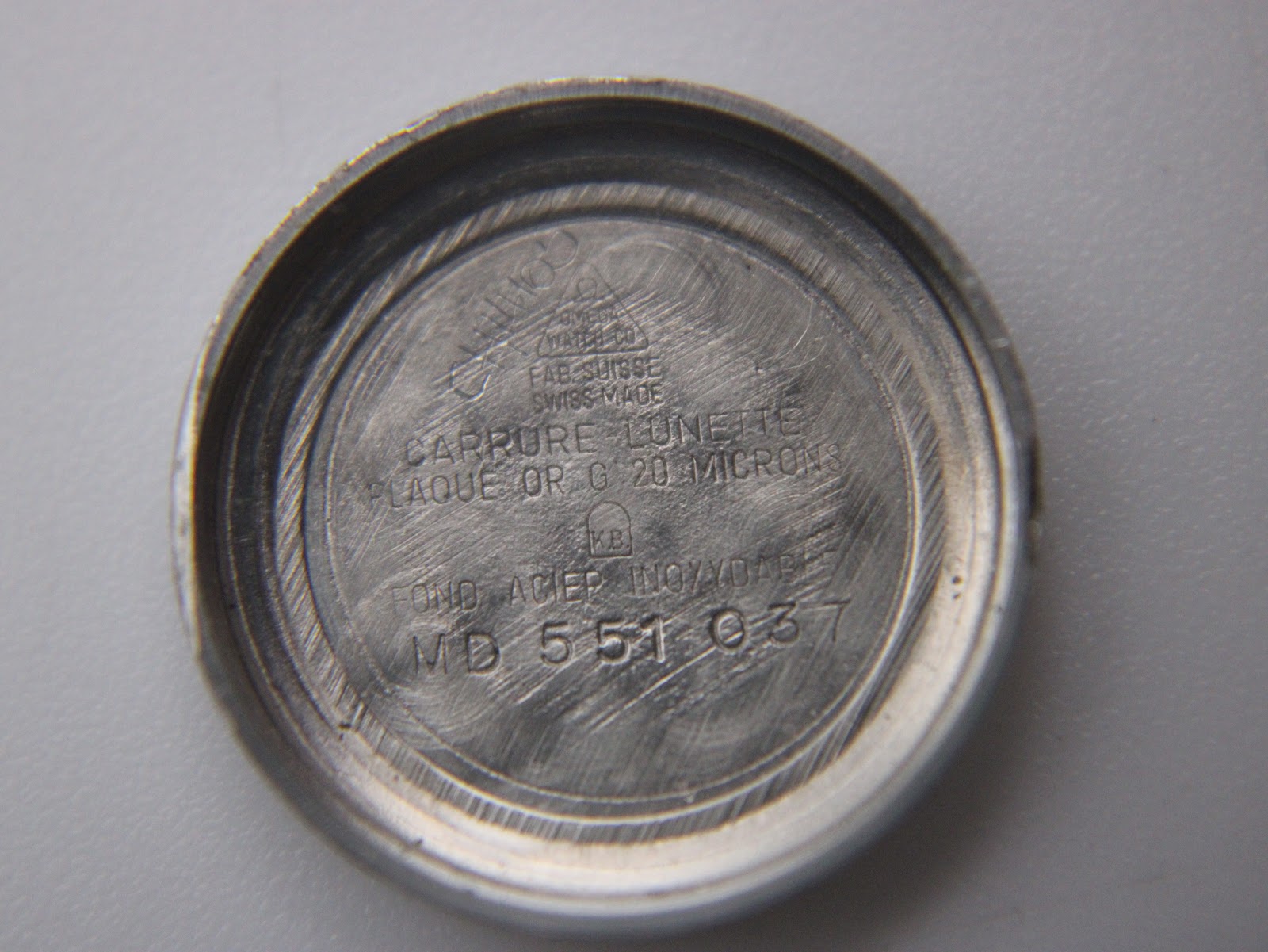 Inside of the Omega De Ville case back, showing 'Plaque Or G 20 Microns' and 'Fond Acier Inoxydable' engravings.