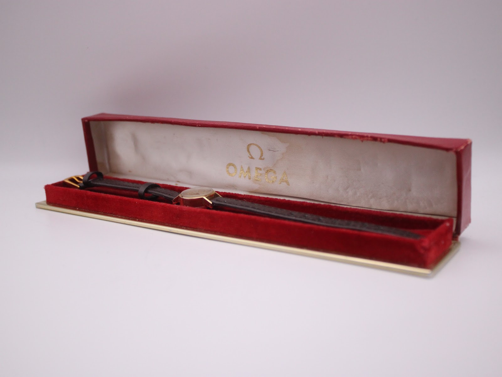 The Omega De Ville watch presented inside its original red Omega presentation box.