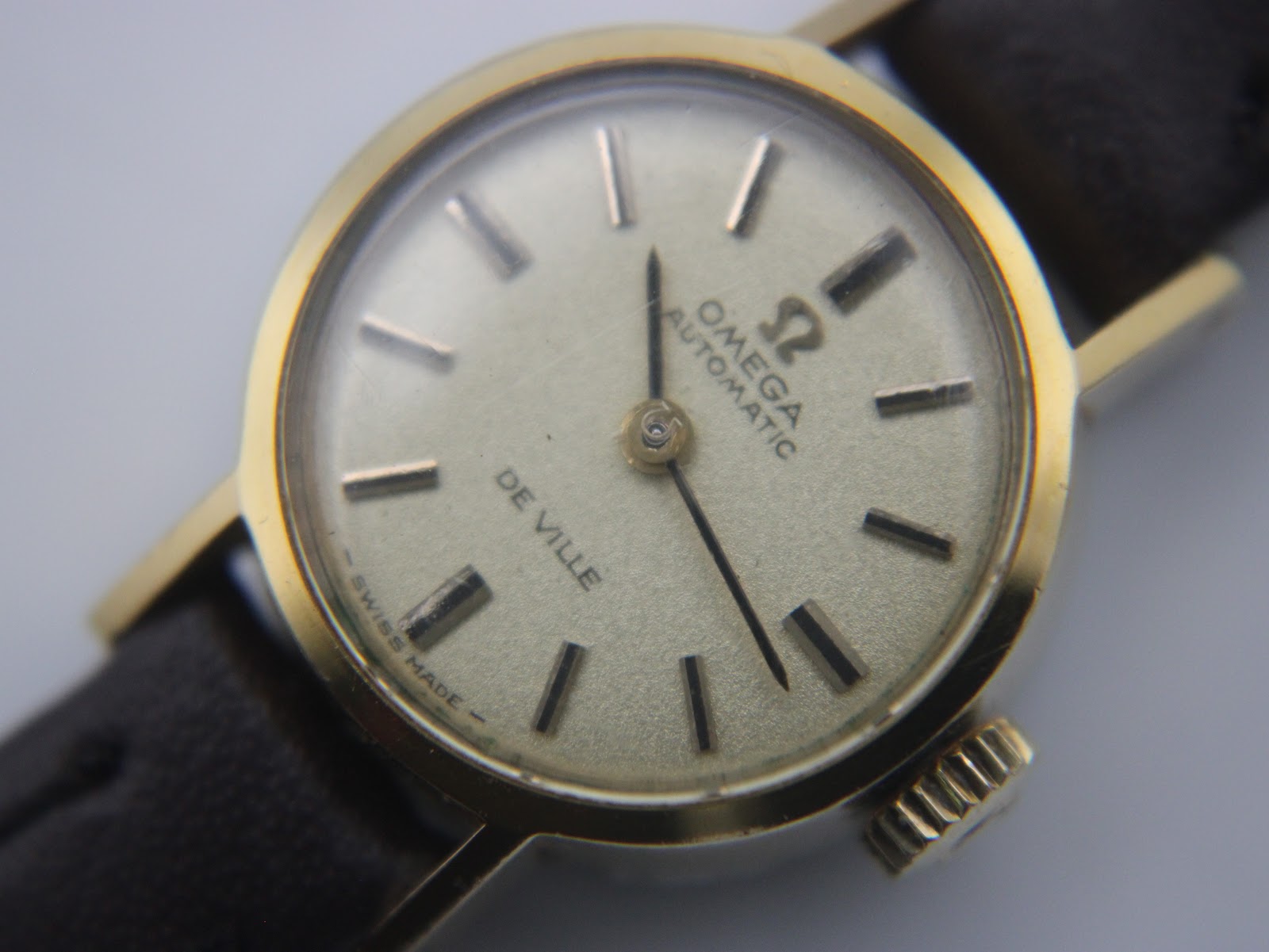 Angled close-up of the Omega De Ville dial, showing the hands, indices, and the 'Swiss Made' text at the bottom.