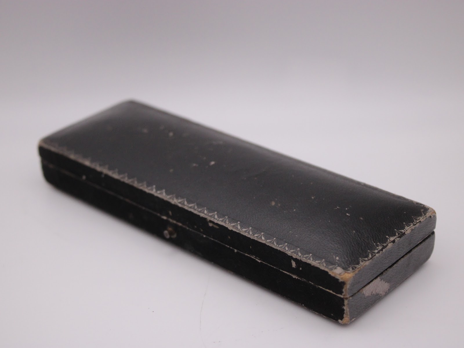 Exterior view of the vintage black watch box, showing wear and textured finish.