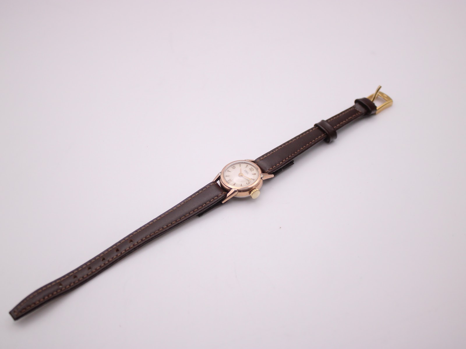 Overhead view of the entire EBEL watch laid flat, displaying the brown leather strap and gold buckle.