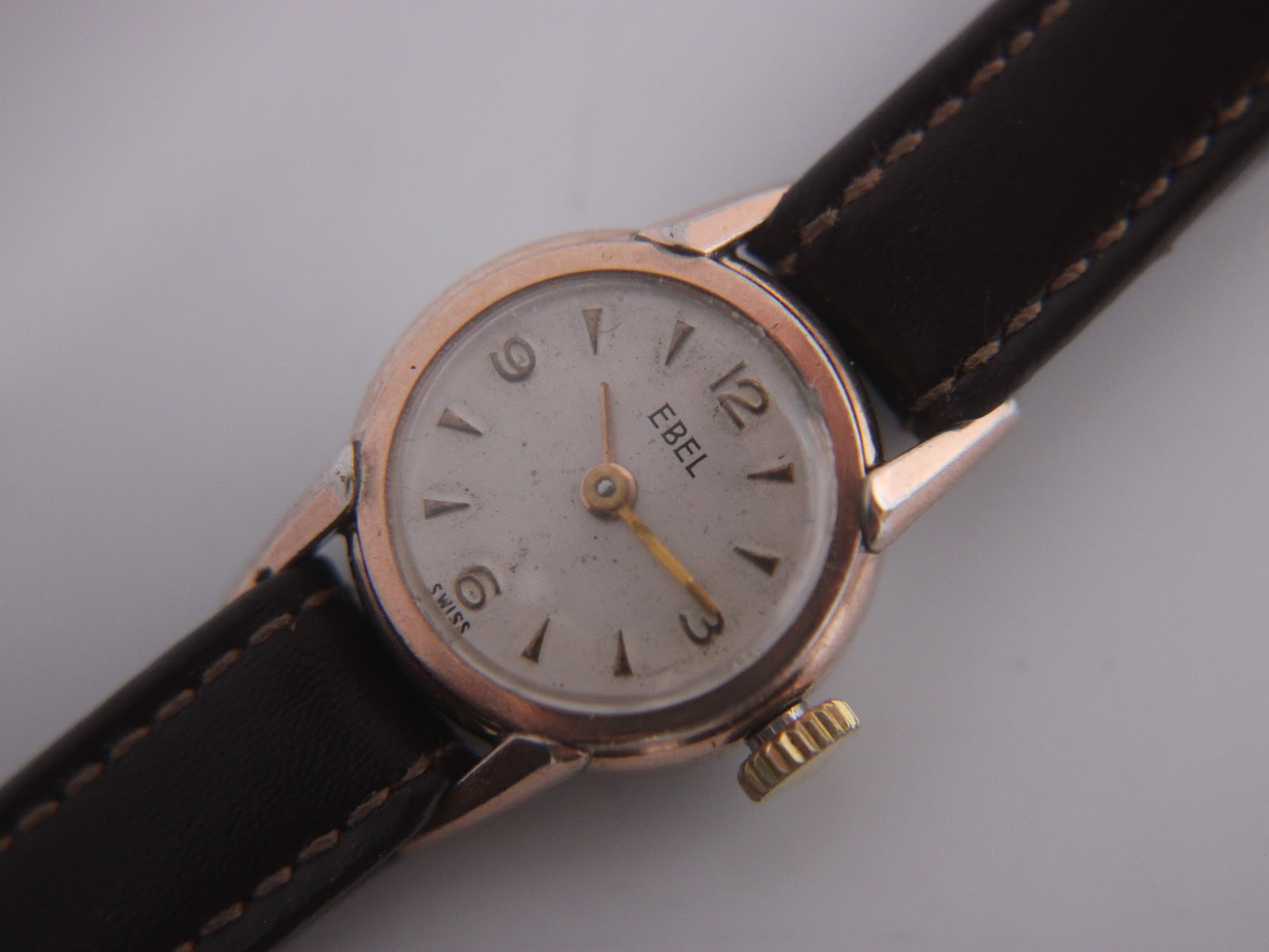 Close-up of the EBEL watch dial, showing the cream face, Arabic numerals, baton indices, and 'EBEL' branding.